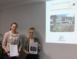Bild vergr&ouml;&szlig;ern: Alina von Germeten und Franke Diehl zeigen ihren Leitfaden durch die Verwaltung mit Beamerpräsentation im Hintergrund
