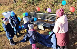 Bild vergr&ouml;&szlig;ern: F&uuml;nf Kinder haben die Plane von der Bank gezogen, sodass die neue Bildungsinsel in Hadem zum Vorschein kommt.
