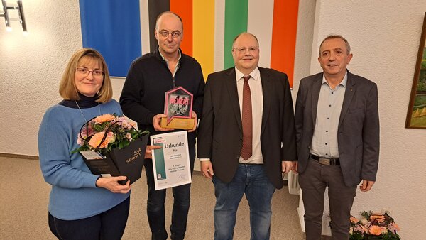 Susanne R&uuml;sing und Dr. Peter Neuhaus nehmen den Pokal, die Urkunde und einen Blumenstrau&szlig; von Stadtverordnetem Michael St&ouml;tzel und B&uuml;rgermeister Kyrillos Kaioglidis entgegen (v. l.)Urkunde