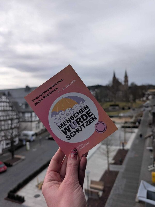Auf dem Foto ist eine Hand zu sehen, die einen Flyer zu den 