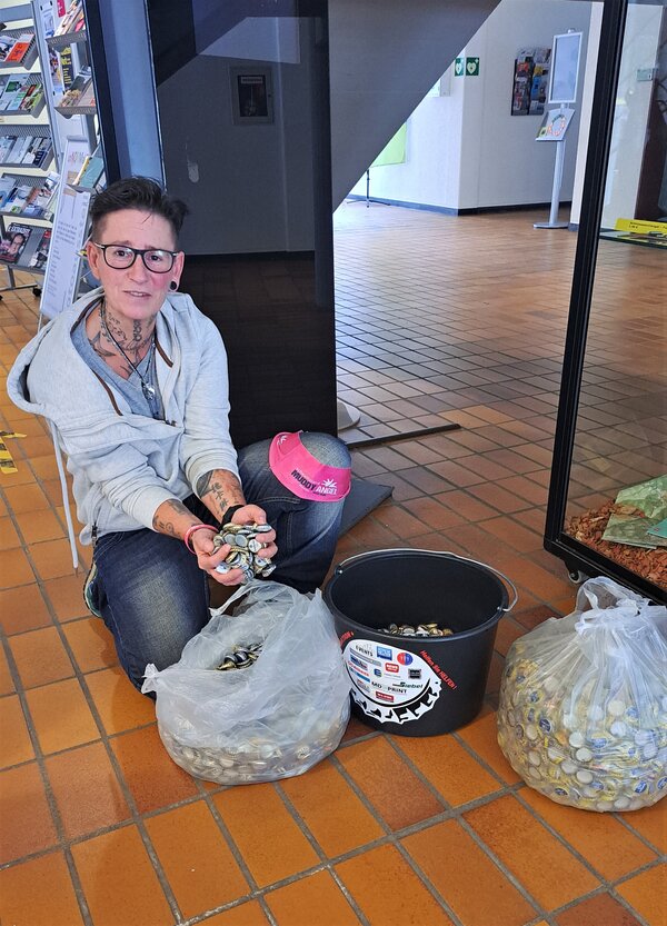 Stephanie Tetzlaff aus Plettenberg &uuml;bergibt im Hilchenbacher Rathaus Tausende Kronkorken. Eine T&uuml;te hat sie vom Muddy Angel Run mitgebracht.