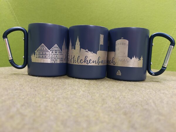 Die neuen Thermobecher zeigen die Hilchenbach-Skyline und haben praktische Karabinerhaken als Henkel.