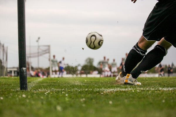&Uuml;ber das Landesprogramm 1000 x 1000 k&ouml;nnen sich Vereine f&uuml;r F&ouml;rderungen bewerben. Das Bild zeigt ein Fu&szlig;ballfeld. Im Vordergrund schie&szlig;t ein Spieler einen Ball, im Hintergrund sind unscharf weitere Spieler und das Tor zu sehen.